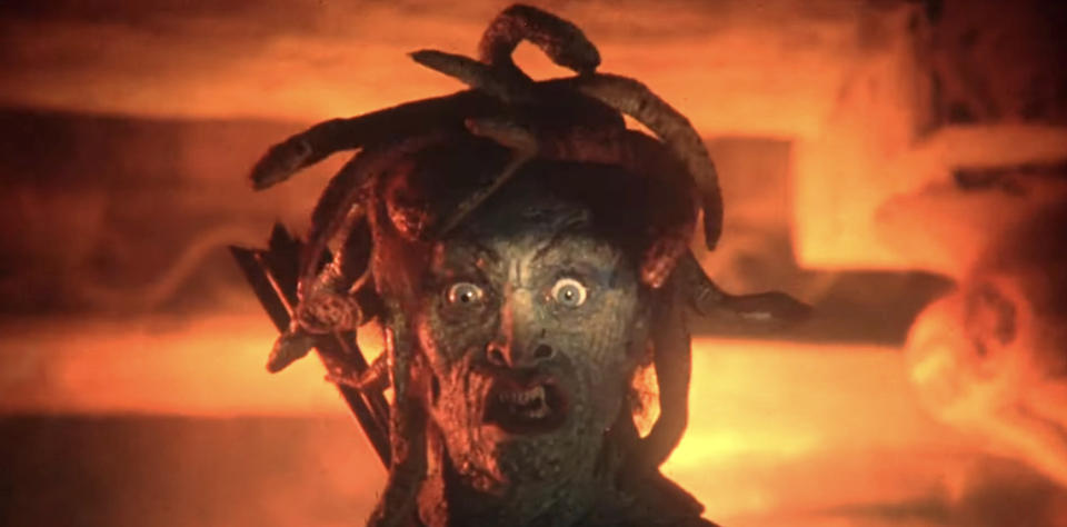 A menacing creature with a human face and snake hair, resembling Medusa, appears in a dramatic, intense scene