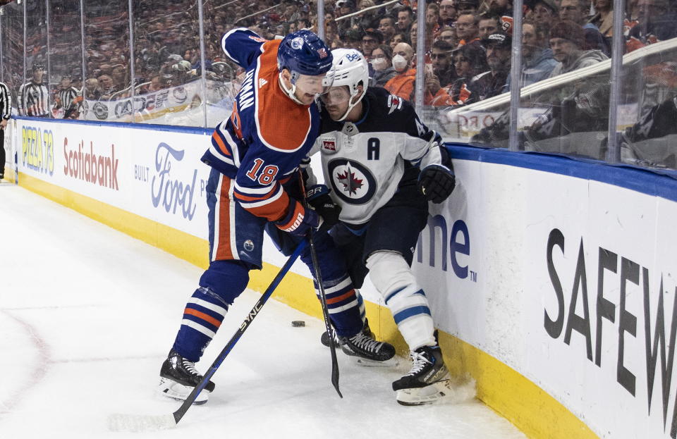 Winnipeg Jets' Josh Morrissey (44) and Edmonton Oilers' Zach Hyman (18) compete for the puck during the first period of an NHL hockey game Friday, March 3, 2023, in Edmonton, Alberta. (Jason Franson/The Canadian Press via AP)