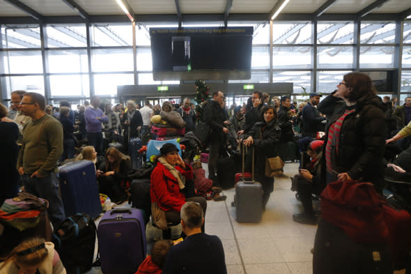 Passengers wait underneath blank departure screens following a power outage at the North Terminal of London Gatwick Airport in Horley, England, Tuesday, Dec. 24, 2013. A severe winter storm has caused major travel problems in Britain, leading to substantial delays Tuesday at London Gatwick Airport and on roads and rail lines at the height of the Christmas travel period. (AP Photo/Sang Tan)