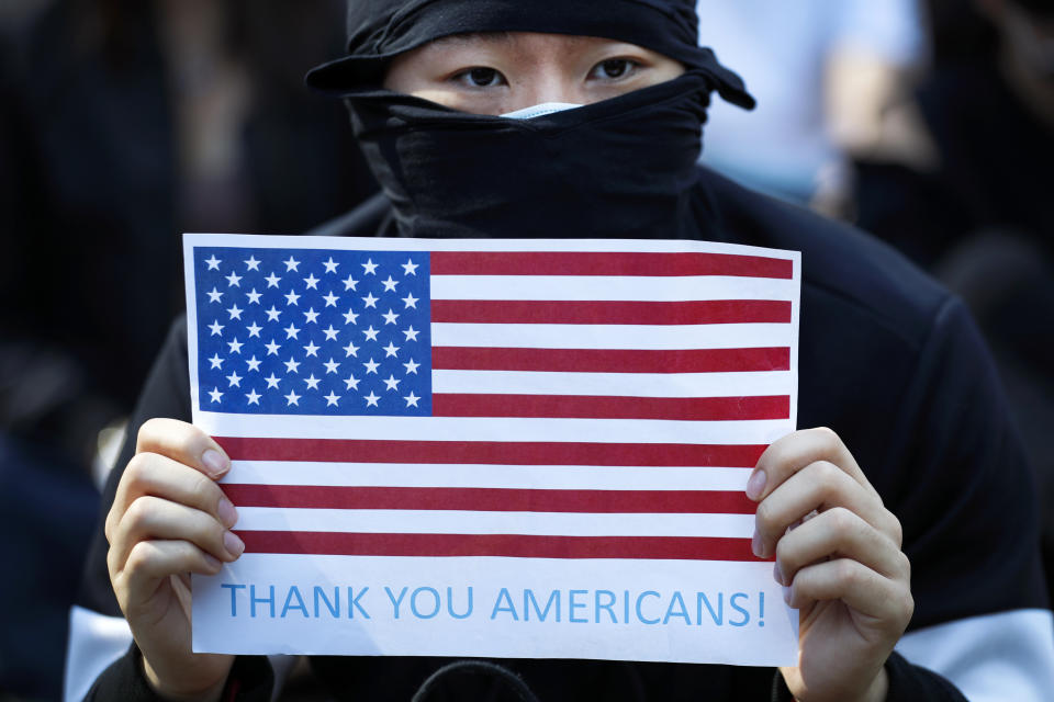 A protester holds a placard carrying an American flag during a rally in Hong Kong, Sunday, Dec. 1, 2019. Hong Kong protesters carrying American flags and banners appealing to President Donald Trump are rallying in the semi-autonomous Chinese territory. (AP Photo/Vincent Thian)