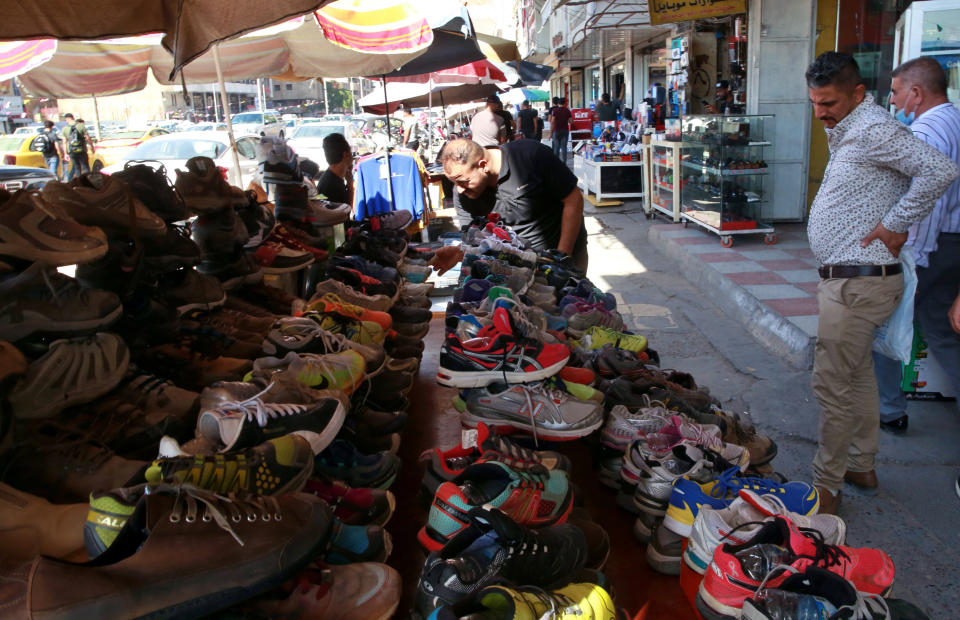 People shop for used shoes at the used-clothes market in Baghdad, Iraq, Tuesday, Oct. 20, 2020. Iraq is in the throes of an unprecedented liquidity crisis, as the cash-strapped state wrestles to pay public sector salaries and import essential goods while oil prices remain dangerously low. (AP Photo/Khalid Mohammed)