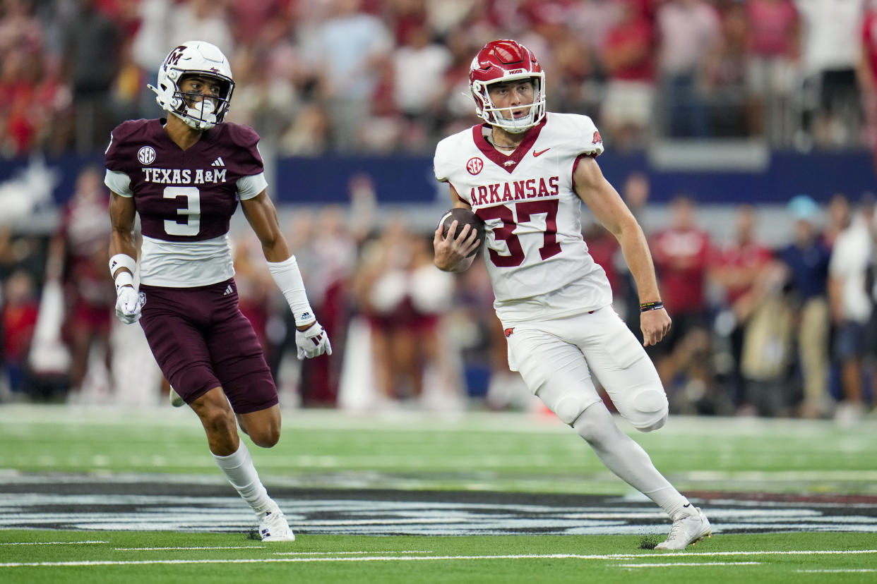 Arkansas punter Devin Bale, right, runs with the ball with Texas A&M defensive back Marcus Ratcliffe in tow while running a fake punt play for a first down during the first half of an NCAA college football game, Saturday, Sept. 28, 2024, in Arlington, Texas. (AP Photo/Julio Cortez)