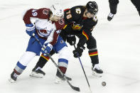 Colorado Avalanche's Samuel Girard, left, and Calgary Flames' Martin Pospisil work for the puck during the third period of an NHL hockey game Tuesday, March 12, 2024, in Calgary, Alberta. (Larry MacDougal/The Canadian Press via AP)