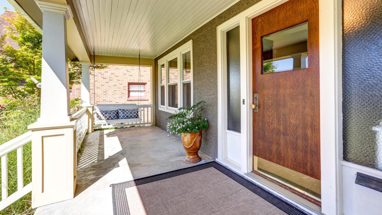 Front covered porch with hanging swing and flower pot.