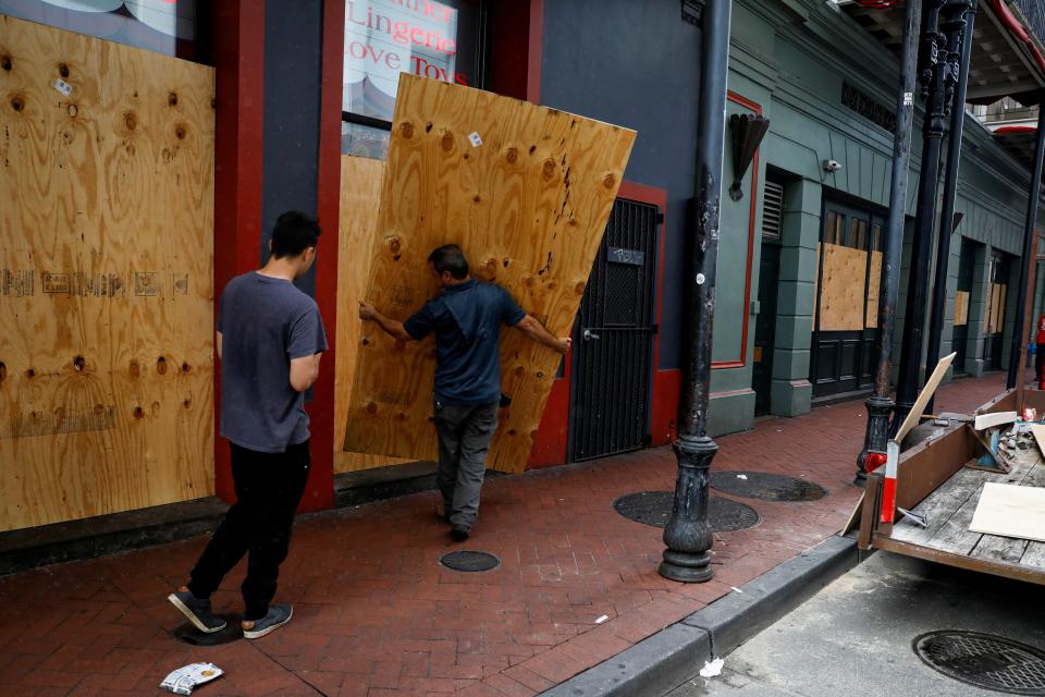 Men place plywood in front of a store in preparation for Hurricane Ida, in New Orleans (REUTERS)