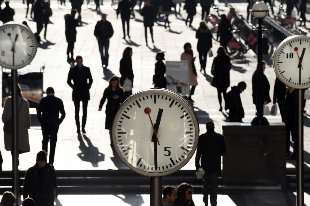 Employees standing under clocks in Canary Whaef