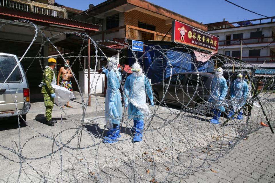 Immigration Department personnel in protective suits are pictured during a raid on illegal immigrants in Selayang Baru amid the enhanced movement control order May 14, 2020. — Picture by Yusof Mat Isa