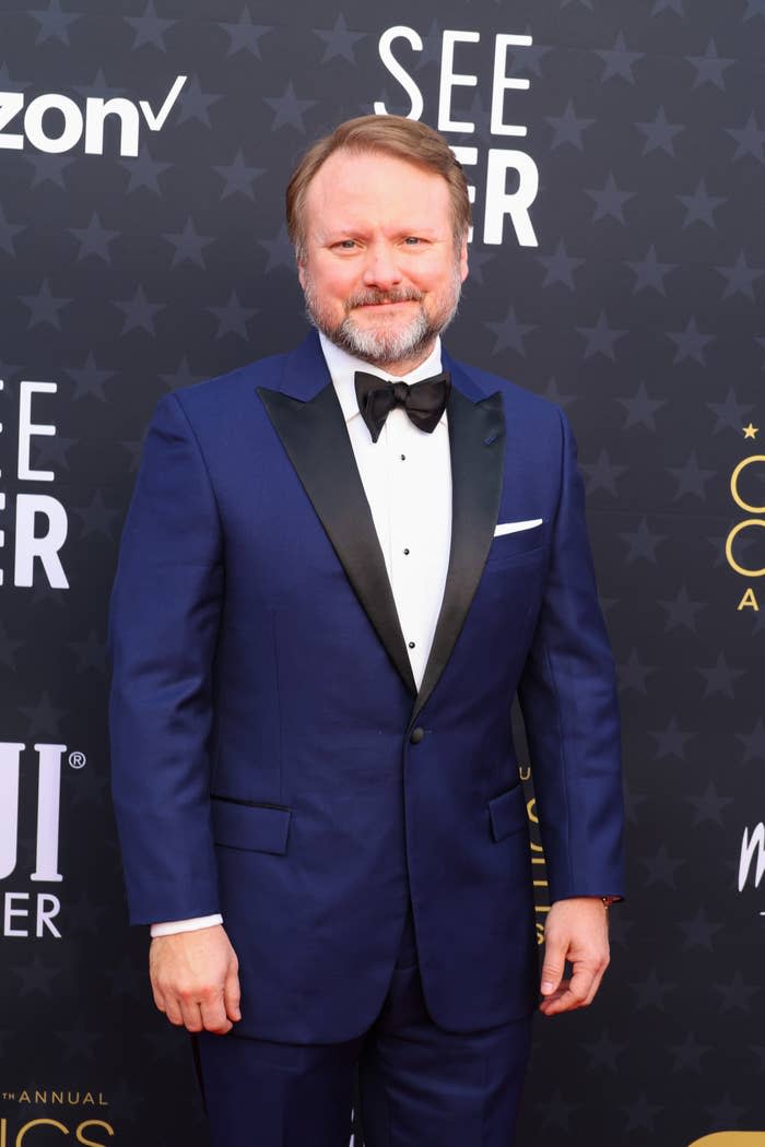 Rian Johnson is on the red carpet wearing a suit with a bow tie and shirt at the Critics' Choice Awards event