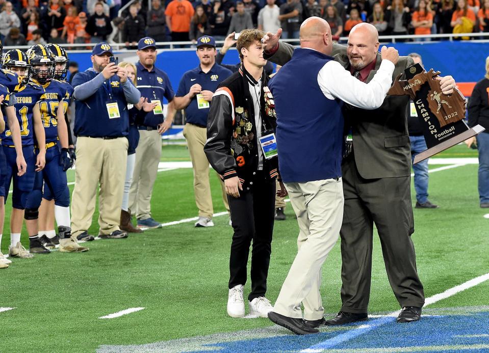 Whiteford head coach Todd Thieken receives a big hug from former head coach Jason Mensing and to receive the Division 8 State Championships at Ford Field Friday.