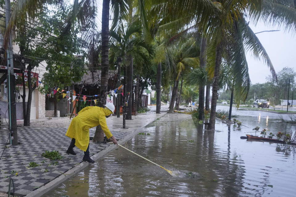 A man unclogs a drain in the aftermath of Hurricane Beryl, in Tulum, Mexico, Friday, July 5, 2024. (AP Photo/Fernando Llano)