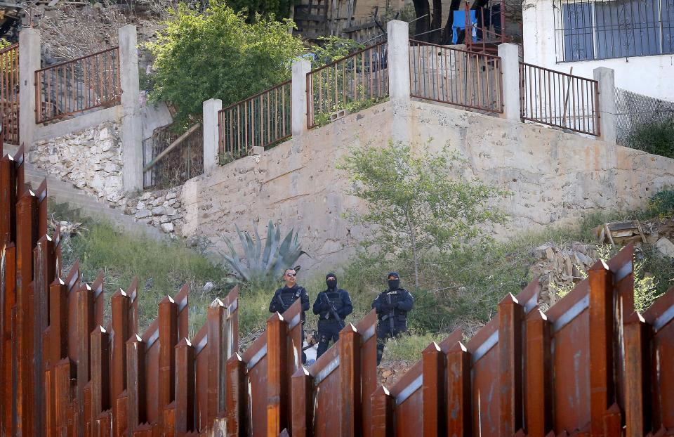 Mexican law enforcement officials watch on the Mexican side of the international border while Boston Archdiocese Cardinal Sean O'Malley leads mass, Tuesday, April 1, 2014, in Nogales, Ariz. A delegation of Roman Catholic leaders celebrated Mass along the U.S.-Mexico border to raise awareness about immigration and to pray for policy changes. (AP Photo/Matt York)