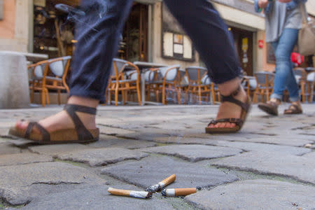 Smoke rises from a burning cigarette butt that is crushed on paving stones along a pedestrian street in Lyon, France, June 14. 2018. The French government wants to end the bane of discarded cigarette butts and will impose new regulations unless tobacco companies come up with proposals to reduce their number. REUTERS/Emmanuel Foudrot 