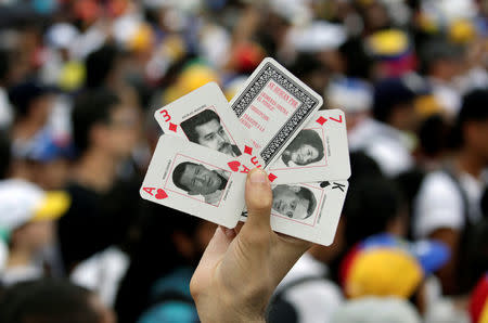 An Opposition supporter holding cards with the image of President Maduro and depicting late President Hugo Chavez takes part in a rally against Venezuela's President Nicolas Maduro's government in Caracas, Venezuela, October 26, 2016. REUTERS/Carlos Garcia Rawlins
