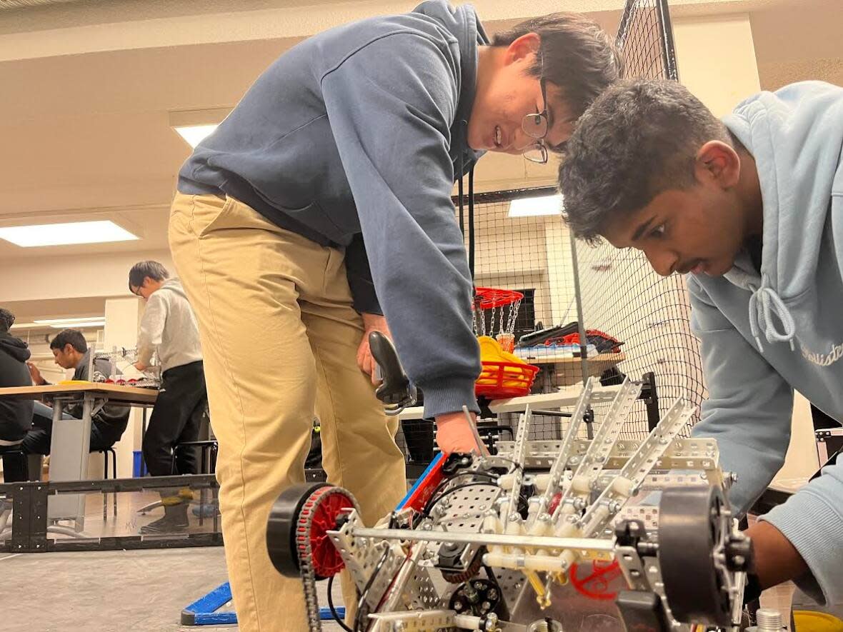 Kevin Zhao and Kartik Ramachandran make adjustments to their robot, 210Z Eclipse, at one of their last few practices before the big tournament.  (Jo Horwood/CBC - image credit)