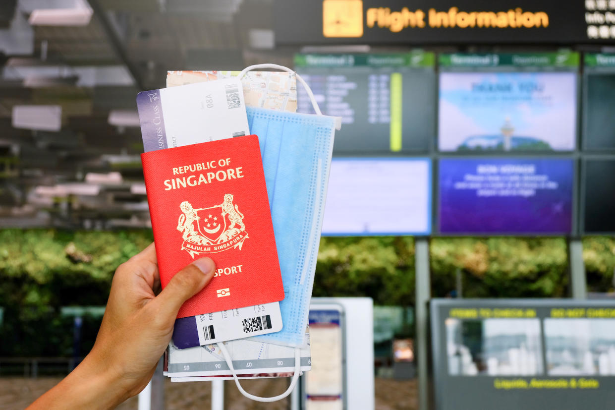 A photo showing a person holding a Singapore passport, boarding pass & mask as ICA advises passport applicants with year-end travel plans to apply now. 