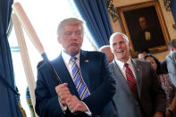 El vicepresidente Mike Pence sonríe mientras Trump sostiene un bate de béisbol en un acto en el que se exhiben productos ‘Made in America’ en la Casa Blanca. (Foto: Carlos Barria / Reuters).