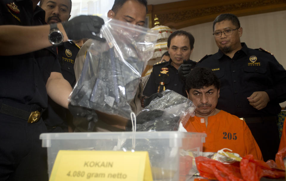 Indonesian custom officers show an evidence as they stand next to Peruvian Jorge Albornoz Gamarra, foreground, during a press conference in Bali, Indonesia on Thursday, Dec. 13, 2018. Indonesian officials say they have arrested five foreigners, including Gamarra, who were attempting to smuggle illegal drugs to the tourist island of Bali. (AP Photo/Firdia Lisnawati)