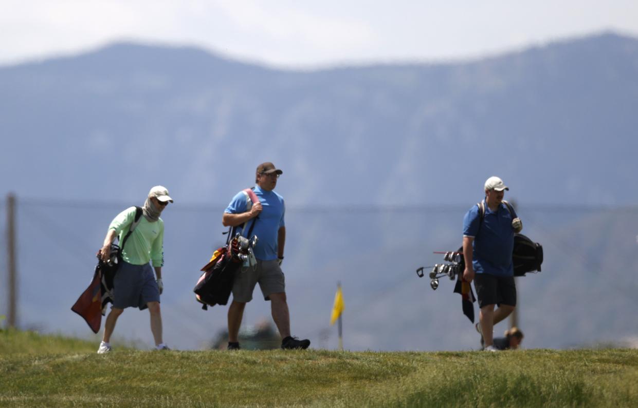 Golfers walk down a fairway on Broken Tee Golf Course on Saturday, May 23, 2020, in Sheridan, Colo. With the relaxation of closures due to the coronavirus pandemic, golfers are able to return to the links in the Denver metropolitan area.