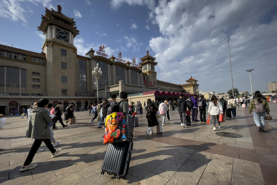 Travelers arrive at Beijing Railway Station to catch their trains in Beijing, Friday, Sept. 29, 2023. Tens of millions of Chinese tourists are expected to travel within their country, splurging on hotels, tours, attractions and meals in a boost to the economy during the 8-day autumn holiday period that began Friday. (AP Photo/Andy Wong)