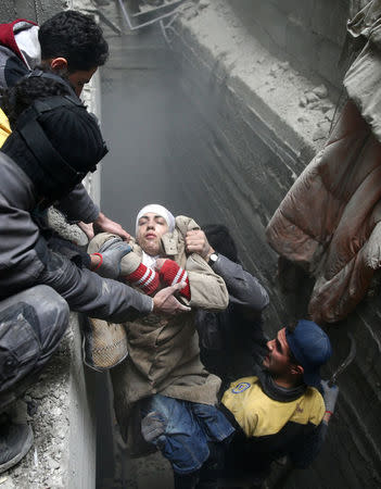 Civil defence help an unconscious woman from a shelter in the besieged town of Douma in eastern Ghouta in Damascus, Syria, February 22, 2018. REUTERS/Bassam Khabieh