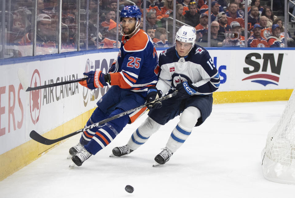 Winnipeg Jets' Rasmus Kupari (15) and Edmonton Oilers' Darnell Nurse (25) battle for the puck during the first period of an NHL hockey game in Edmonton, Alberta, Saturday, Oct. 21, 2023. (Jason Franson/The Canadian Press via AP)