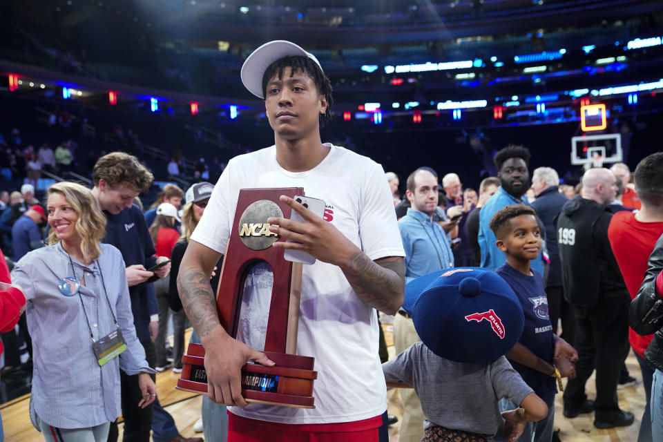 Florida Atlantic's Giancarlo Rosado holds the trophy as Florida Atlantic players celebrate after defeating Kansas State in an Elite 8 college basketball game in the NCAA Tournament's East Region final, Saturday, March 25, 2023, in New York. (AP Photo/Frank Franklin II)