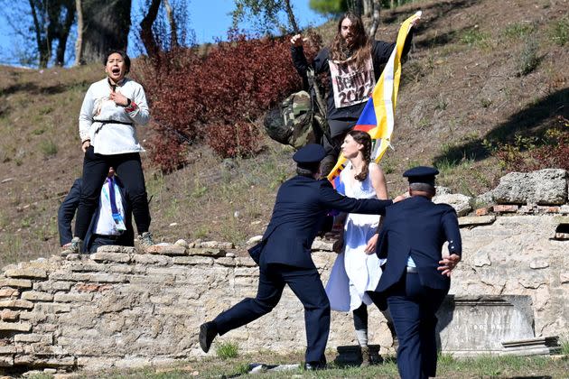 Security officers stop three protesters holding a banner and a Tibetan flag as they crash the flame lighting ceremony for the Beijing 2022 Winter Olympics at the Ancient Olympia archeological site. (Photo: ARIS MESSINIS via Getty Images)