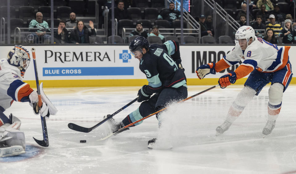 Seattle Kraken forward Ryan Donato, center, takes a shot on New York Islanders goalie Ilya Sorokin, left, and defenseman Noah Dobson during the second period of an NHL hockey game, Sunday, Jan. 1, 2023, in Seattle. (AP Photo/Stephen Brashear)