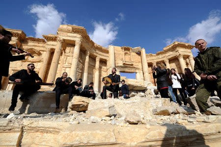 A Russian soldier stands near Syrian musicians as they play their instruments while resting on damage in the amphitheater of the historic city of Palmyra, Syria March 4, 2017. REUTERS/Omar Sanadiki