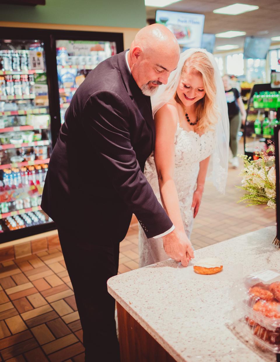 A bride and groom cut a doughnut in a gas station.