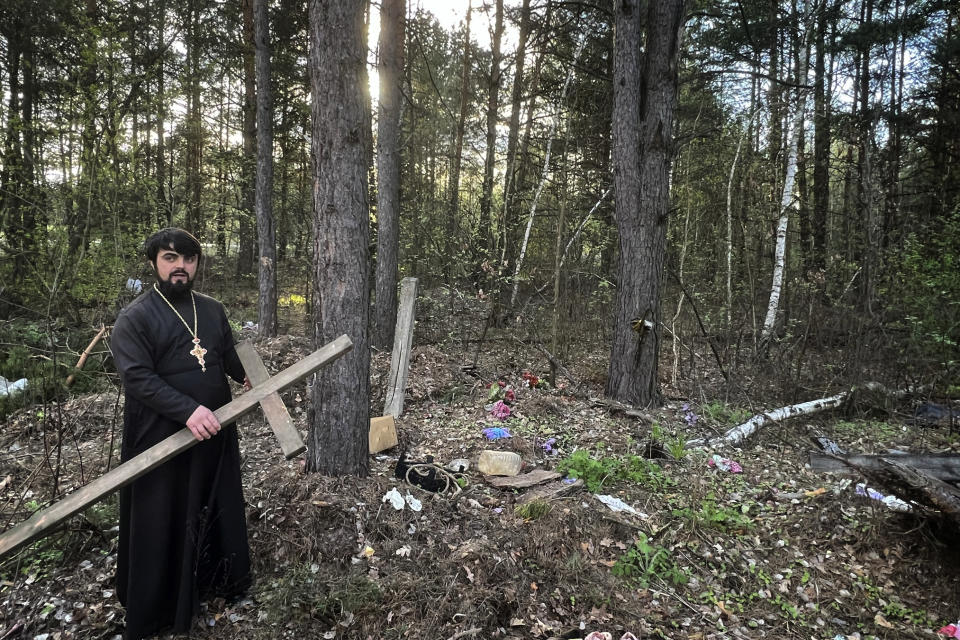 Father Vasyl Bentsa stands at the site in a forest in Zdvyzhivka, Ukraine, where he dug a temporary grave for Mykola "Kolia" Moroz, 47, and four other men. Police left potential evidence of war crimes behind when they exhumed the bodies. (AP Photo/Erika Kinetz)