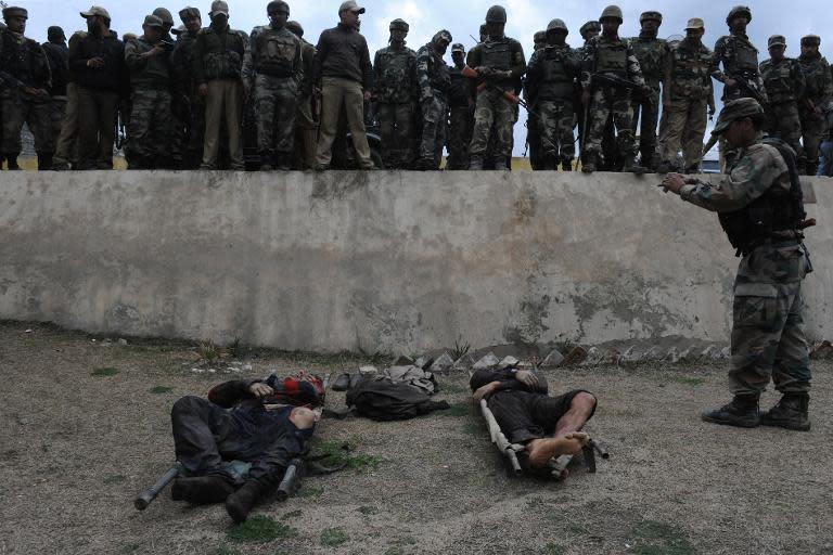 Indian soldiers look over the bodies of suspected militants, who were killed following an attack on policemen guarding the home of a pro-India politician, at a police station in Khrew on April 13, 2014