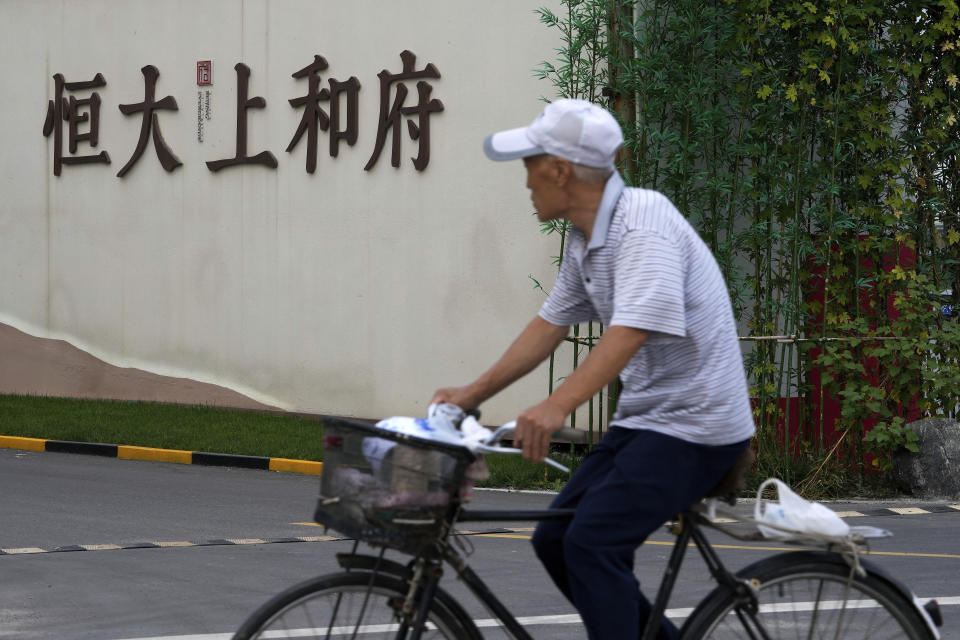 A man bicycles past an Evergrande new housing development in Beijing, Wednesday, Sept. 15, 2021. One of China's biggest real estate developers is struggling to avoid defaulting on billions of dollars of debt, prompting concern about the broader economic impact and protests by apartment buyers about delays in completing projects. Rating agencies say Evergrande Group appears likely to be unable to repay all of the 572 billion yuan ($89 billion) it owes banks and other bondholders. That might jolt financial markets, but analysts say Beijing is likely to step in to prevent wider damage. (AP Photo/Andy Wong)