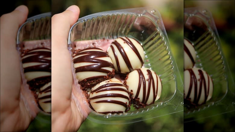 Hand holding tub stripy chocolate snacks