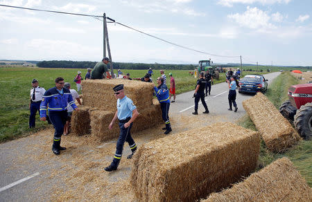 Cycling - Tour de France - The 218-km Stage 16 from Carcassonne to Bagneres-de-Luchon - July 24, 2018 - Police officers remove hay bales off the road after a protest. REUTERS/Stephane Mahe