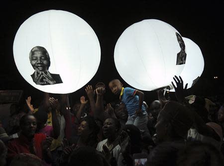 A boy looks on in front of balloons bearing a picture of former South African President Nelson Mandela on Vilakazi Street in Soweto, where Mandela resided when he lived in the township, December 7, 2013. REUTERS/Siphiwe Sibeko