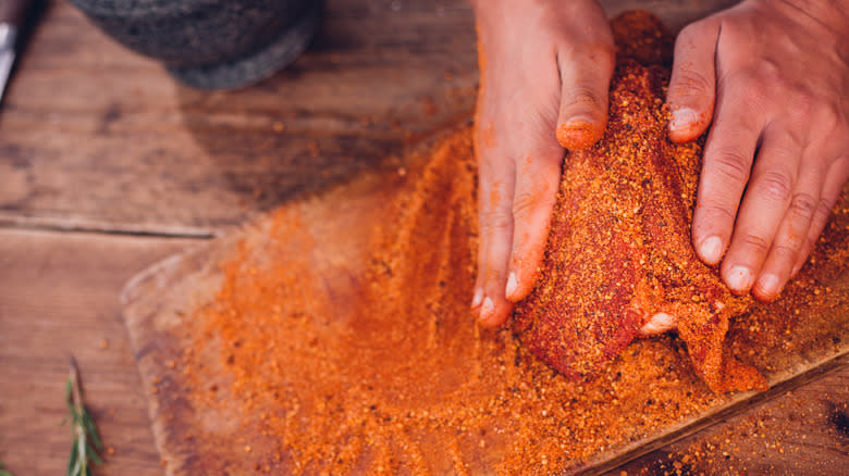 Person rubbing spice blend on pork