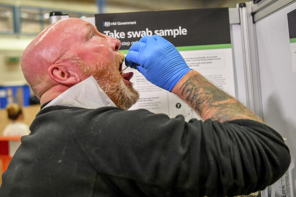 A testing staff member completes a lateral flow test swab, mandatory before opening to the public, at Rhydycar leisure centre in Merthyr Tydfil, Wales, Saturday, Nov. 21, 2020. where mass coronavirus testing begins following a two-week "firebreak" lockdown. (Ben Birchall/PA via AP)