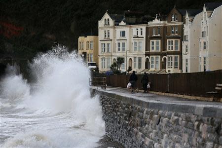 People walk along the promenade as waves crash against the seafront at Dawlish in Devon, south west England October 28, 2013. REUTERS/Stefan Wermuth