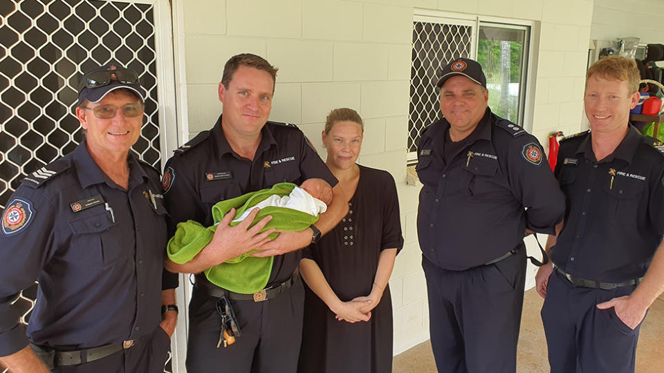 The firefighter crew pose with the baby during their return visit.