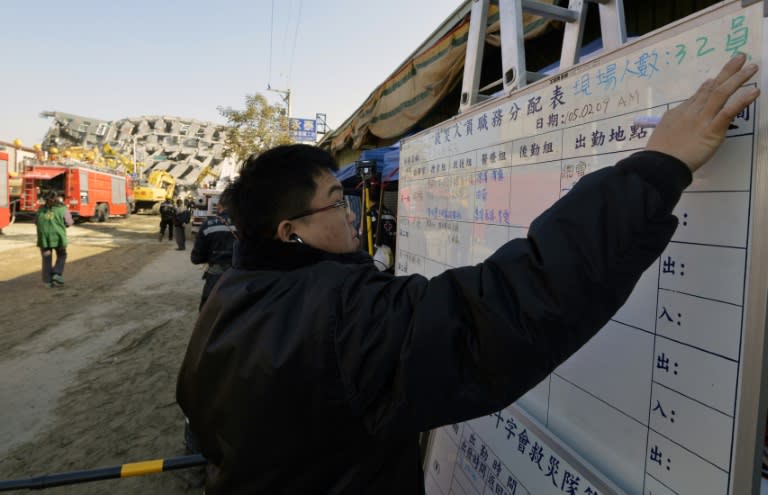 A Taiwanese rescuer updates the information notice board in front of the collapsed Wei-Kuan complex in Tainan, on February 9, 2016