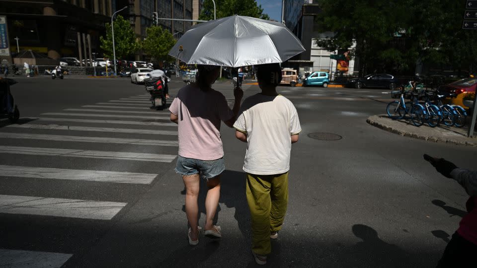 People shelter from the sun as they cross a road during a heatwave in Beijing on July 7, 2023. - Greg Baker/AFP/Getty Images