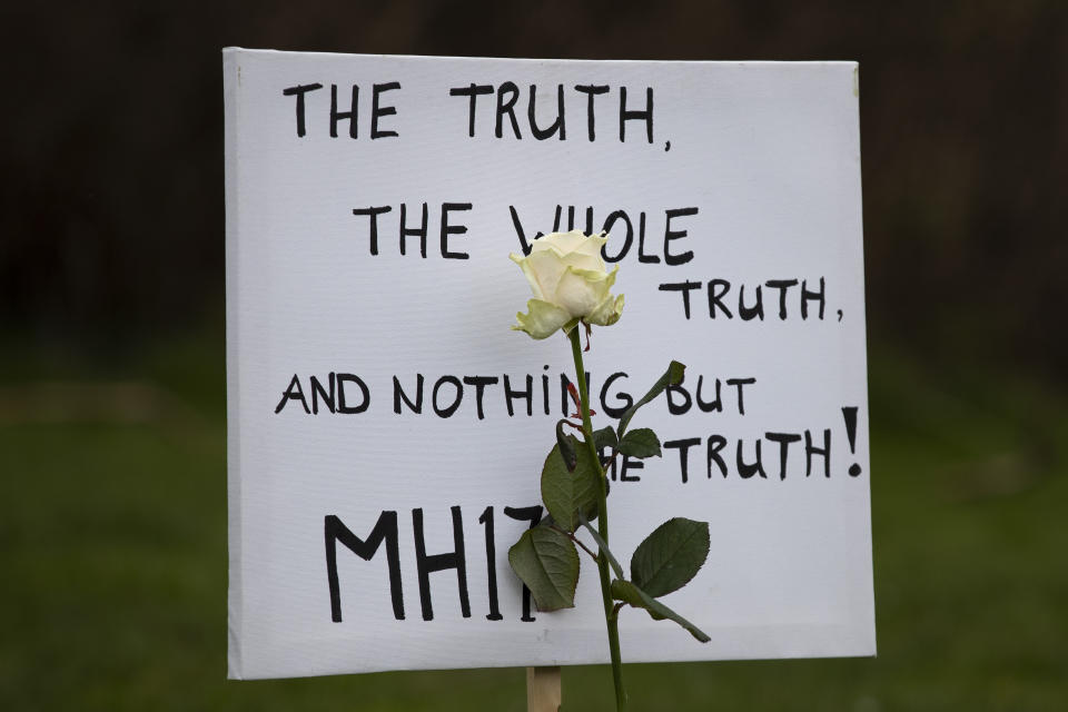 A sign and a rose are placed next to 298 empty chairs, each chair for one of the 298 victims of the downed Malaysia Air flight MH17, are placed in a park opposite the Russian embassy in The Hague, Netherlands, Sunday, March 8, 2020. A missile fired from territory controlled by pro-Russian rebels in Ukraine in 2014, tore the MH17 passenger jet apart killing all 298 people on board. United by grief across oceans and continents, families who lost loved hope that the trial which starts Monday March 9, 2020, will finally deliver them something that has remained elusive ever since: The truth. (AP Photo/Peter Dejong )