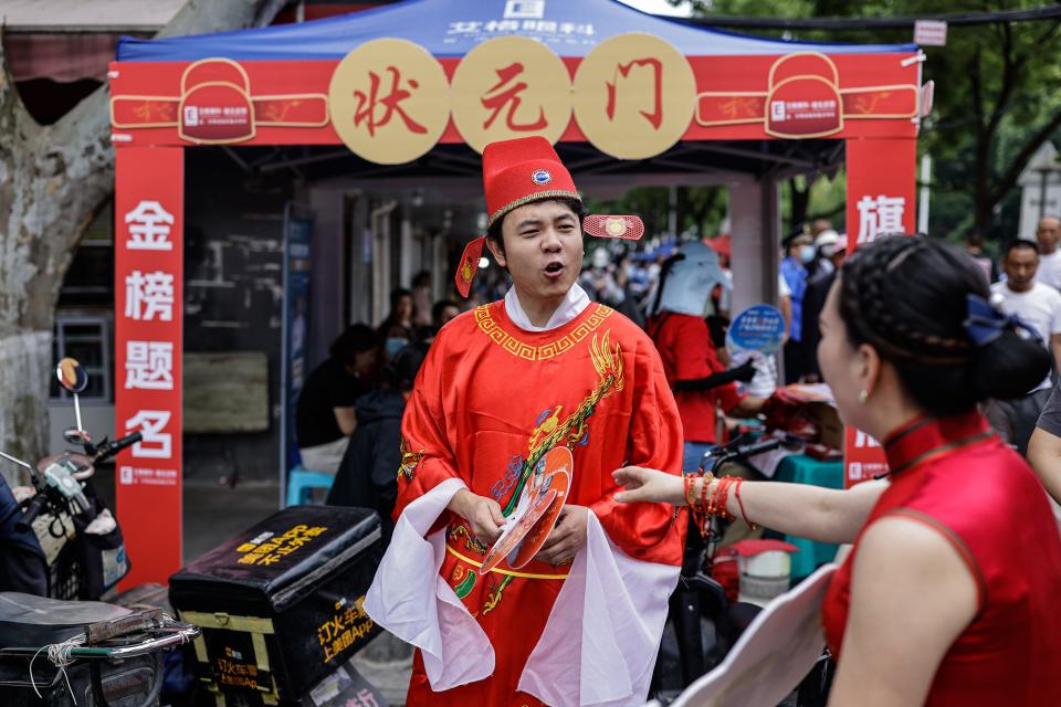 A volunteer dressed to resemble the number one scholar in ancient China, sends blessings to examinees during the national college entrance exams on June 7, 2023 in Wuhan, Hubei province, China. China's annual college entrance exam, better known as the Gaokao, kicked off on Wednesday morning with a record 12.91 million candidates signing up for perhaps the world's most gruelling test.