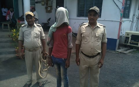 This photo taken on May 6, 2018 shows an alleged rapist (C) being held by Indian police, in the case of a 17-year-old girl who was raped and set on fire