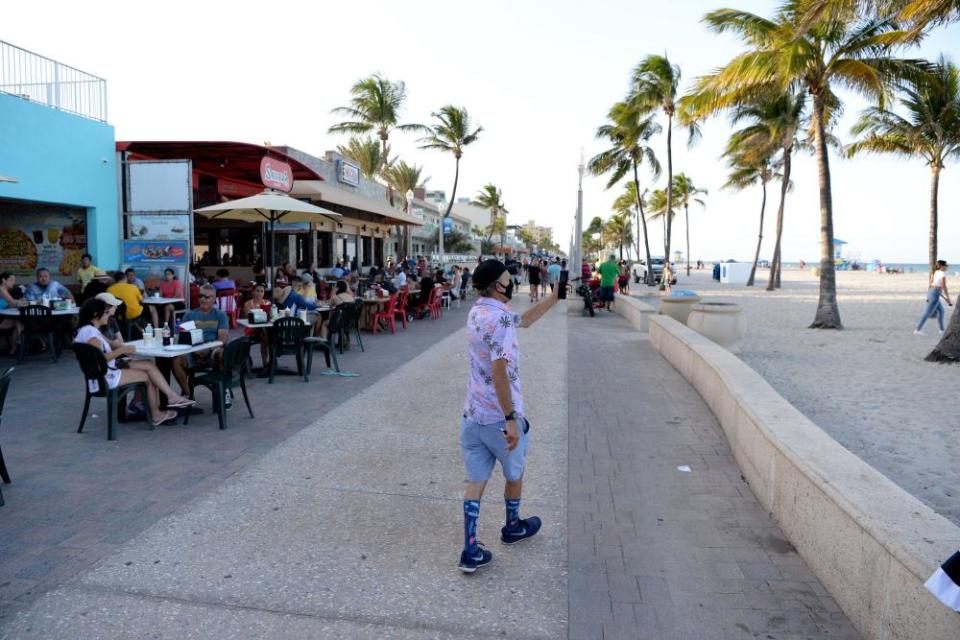 People walk on the Hollywood Beach Boardwalk as Florida reports another surge in coronavirus cases, on 26 June.