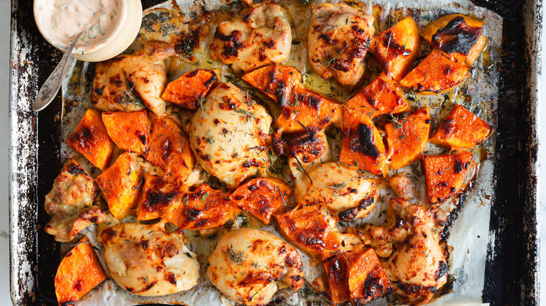 Baked chicken and squash with yogurt on baking sheet