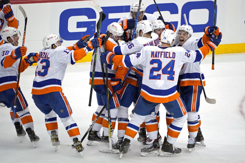 The New York Islanders celebrate a winning overtime goal by Kyle Palmieri in Game 1 of an NHL hockey Stanley Cup first-round playoff series against the Pittsburgh Penguins in Pittsburgh, Sunday, May 16, 2021. (AP Photo/Gene J. Puskar)