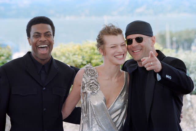 <p>Michel GANGNE/getty</p> (Left-right:) Chris Tucker, Milla Jovovich and Bruce Willis in 1997