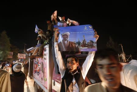 A supporter of Afghan presidential candidate Ashraf Ghani holds a poster as he celebrates in the street after the Independent Election Commission (IEC) announced preliminary results in Kabul July 7, 2014. REUTERS/Omar Sobhani